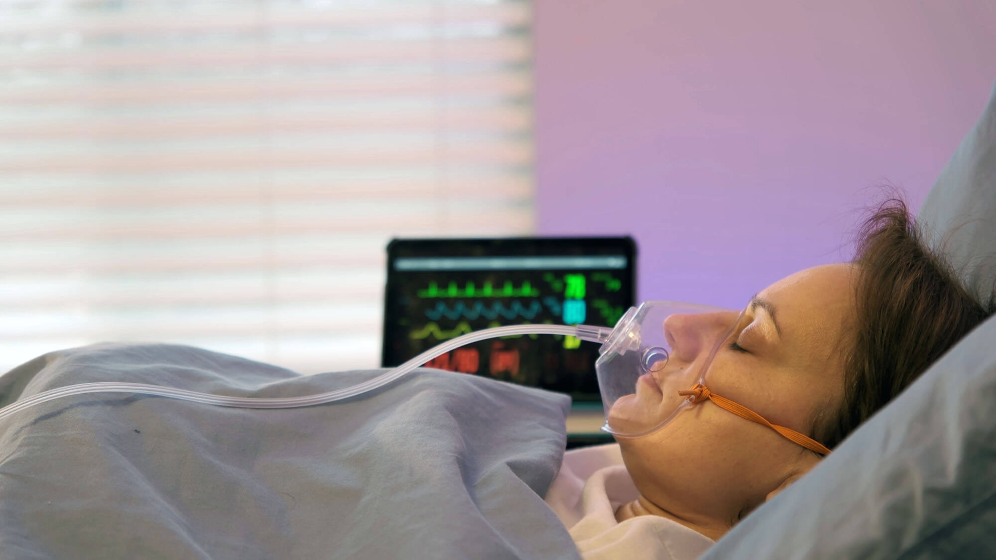 Still Image of Side View Of Mature Caucasian Woman Wearing Oxygen Mask Lying In Bed In Room Of Clinic Close Up